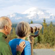 Couple enjoying the views of Mt. Blackburn - woman looking through binoculars on the Copper River Princess property