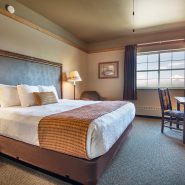 Guest room photo showing king bed, arm chair, window and desk and chair.