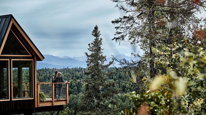 Two people stand on the deck of the treehouse at Mt McKinley Princess Wilderness Lodge