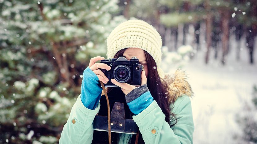 A woman looks through a camera, ready to take a picture.